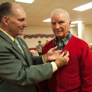 State Rep.Stephen Barrar places a pin on Floren Wayne "Mac" McNicholas who served in WWII, Korea and Vietnam.