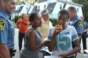 Kennett Square Police Officer Jonhathan Ortiz (from left) enjoys watching Aalana Vasquez and Johnnette Boddy devour their pizza.
