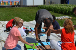 Lynne Filion (left) and Jan Michener (right) from Arts Holding Hands and Hearts, Inc. assist students in translating the teens' ideas into a project entitled "Art Pallets for the Garden."