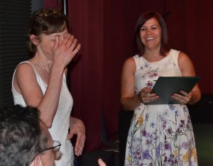 Overcome by the fuss, Carol Intintoli covers her face as Teresa DelCampo from state Sen. Tom Killion's office prepares to read another citation.